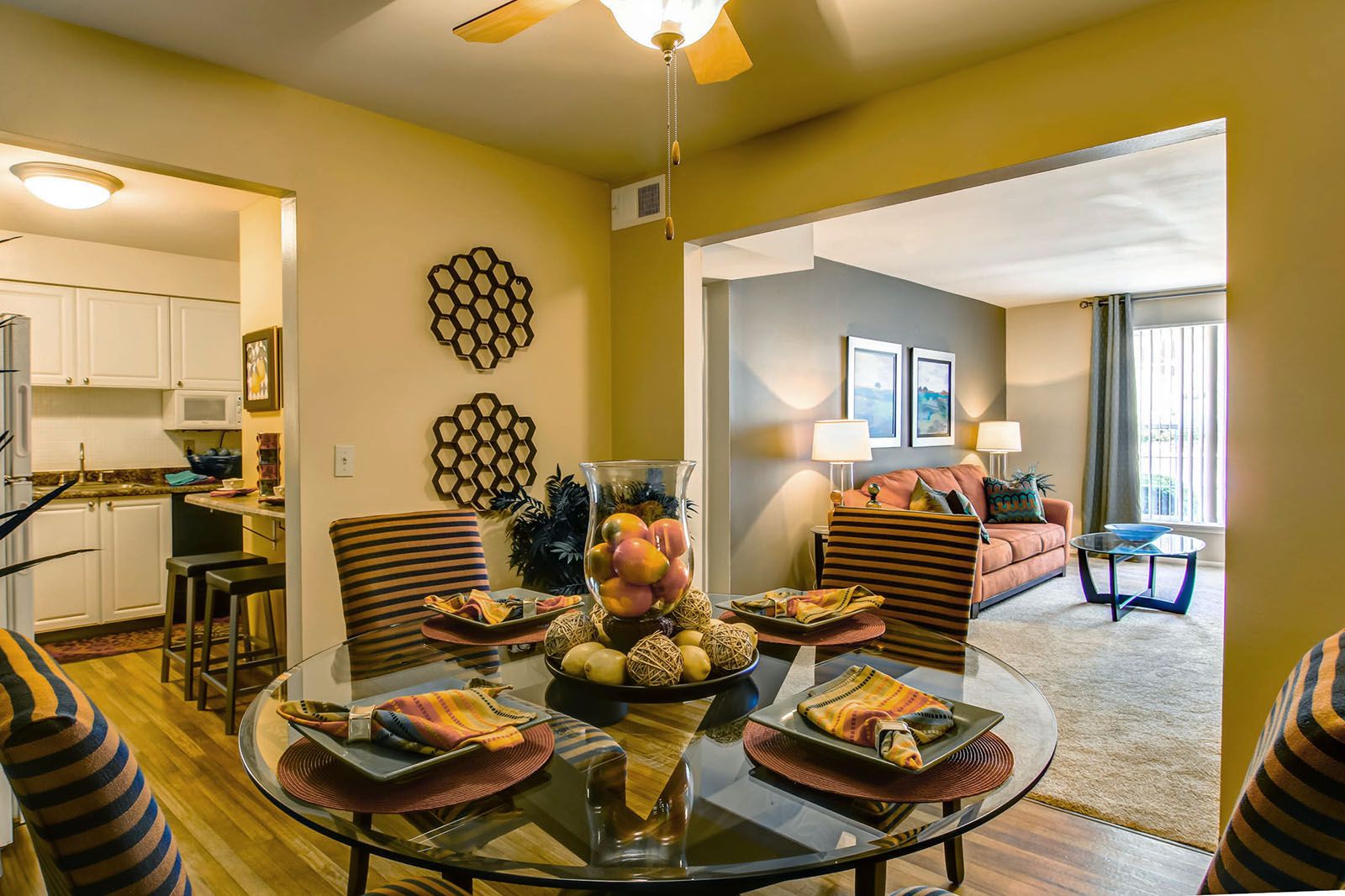Rockwood Apartments Modern dining area with a glass table, adjacent to a cozy living room and a view into the kitchen.